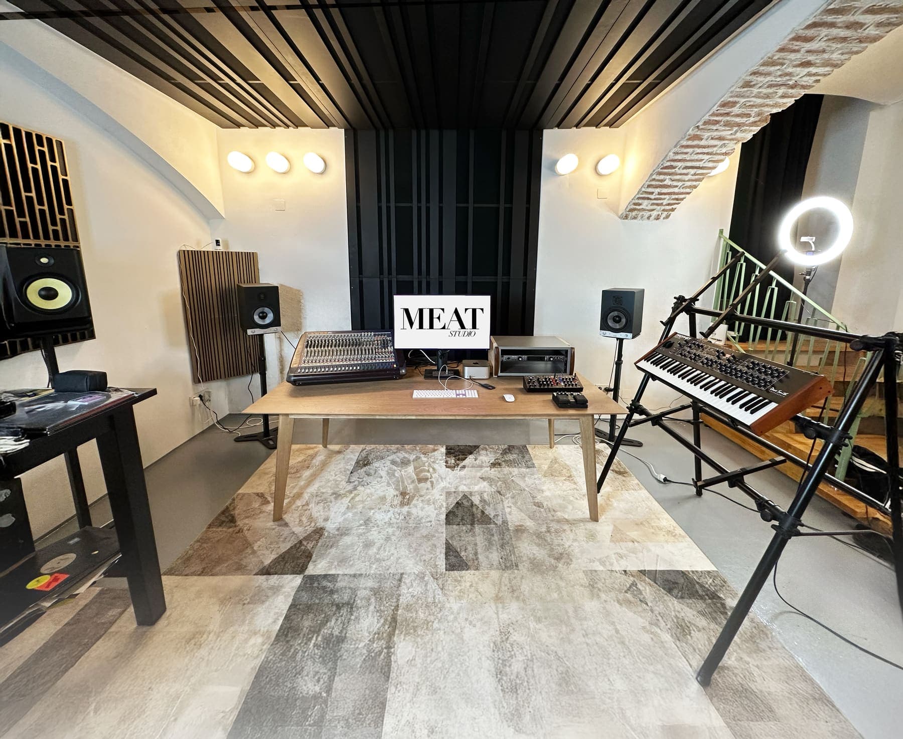 The recording room at MEAT Studio: a bright vaulted room with a wooden ceiling, a large table, a mixing desk, studio monitors and a synthesizer on a stand.