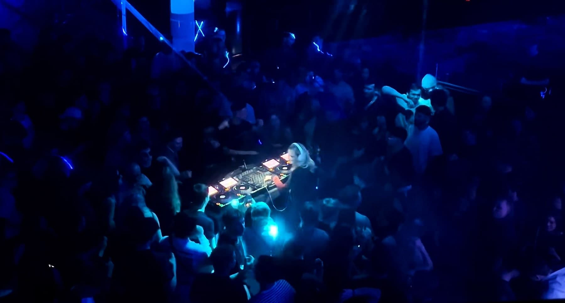 Annika Stein at the decks, shot from above, the crowd all around her in blue light.
