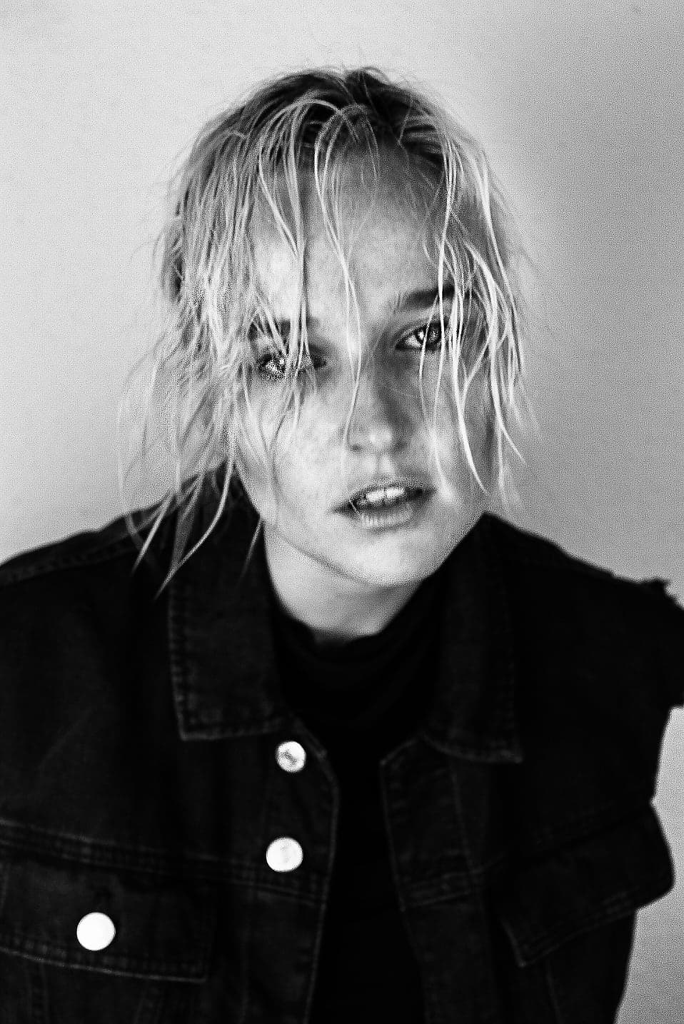 Annika Stein in black and white, denim jacket, hair across her face, looking straight into the camera.