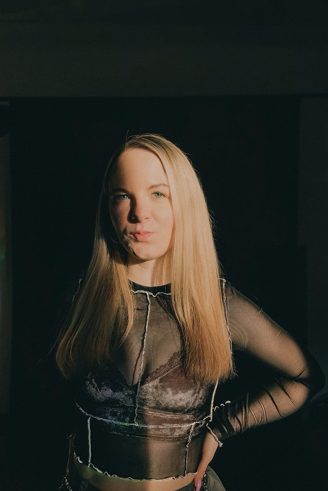 Violetta in half darkness, a strip of light across her face.